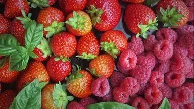 五彩缤纷的浆果背景。绿叶，草莓，覆盆子，特写旋转背景。采购产品生物水果，健康的饮食，自助餐，饮食.
